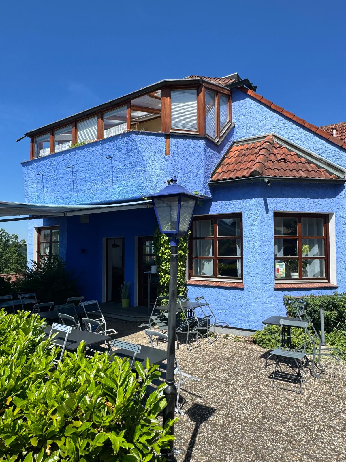 Terrasse mit Außenbestuhlung an der blauen Fassade
